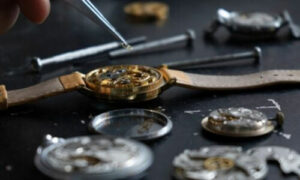 orologio smontato su cui un orologiaio sta cercando di riparare l'ingranaggio