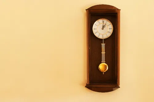 Immagine di un orologio a pendolo con una mano che lo regola, indicando la necessità di manutenzione per mantenere l'orologio in buone condizioni.